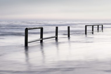 Wooden fence in sea water at dusk